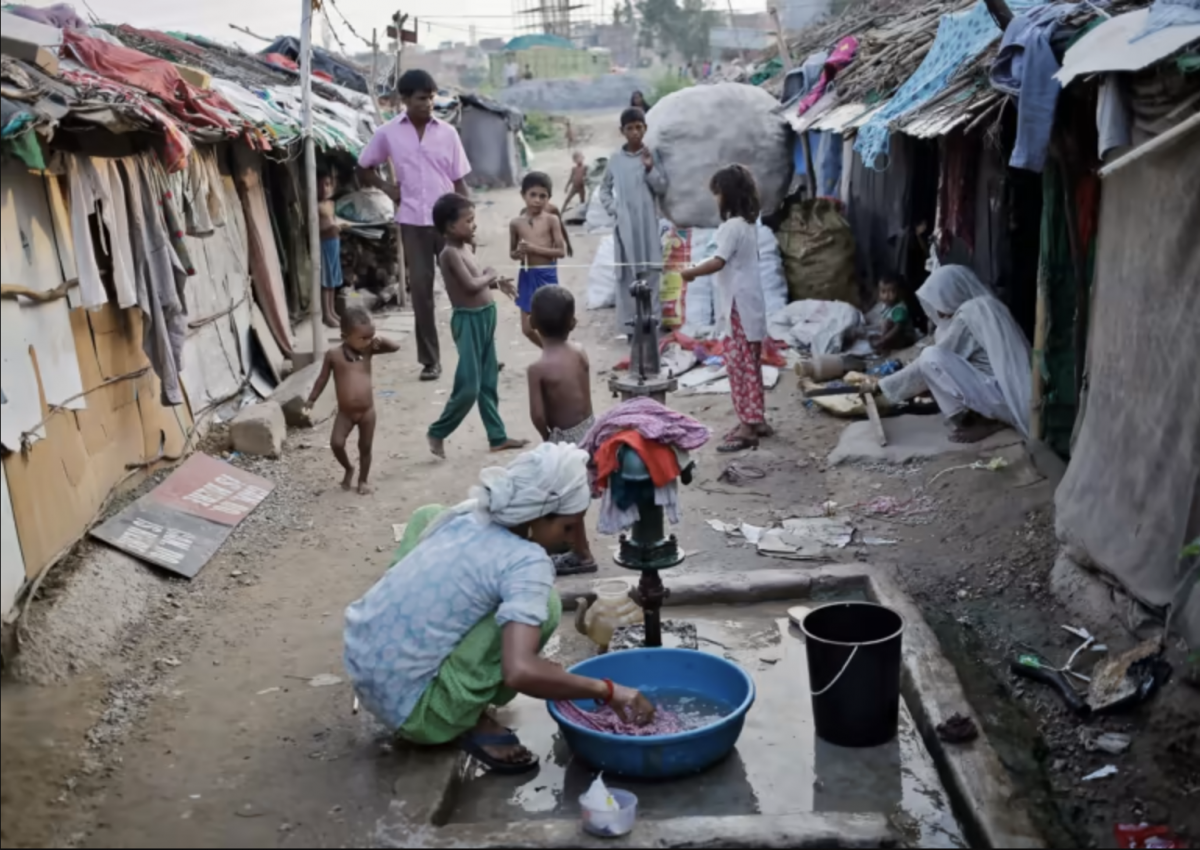 A Rohingya woman from Myanmar washes clothes as children play in a refugee camp in New Delhi in 2014. (Getty Images)